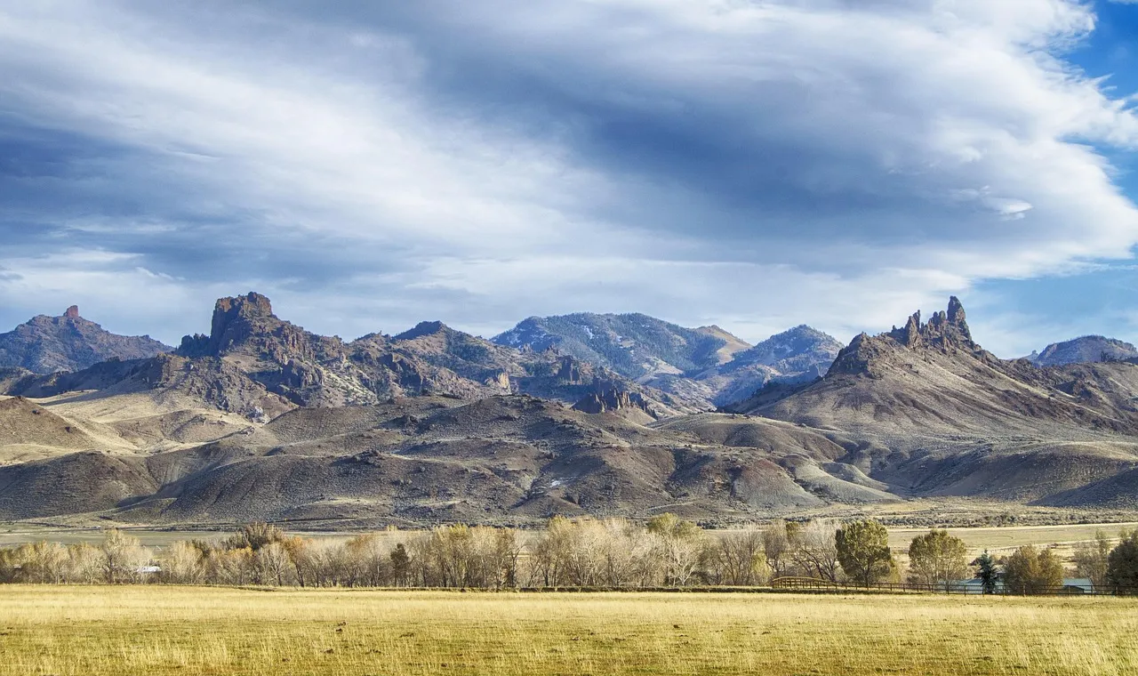 Open Wyoming ranchland under a wide sky, dry grass running to low hills