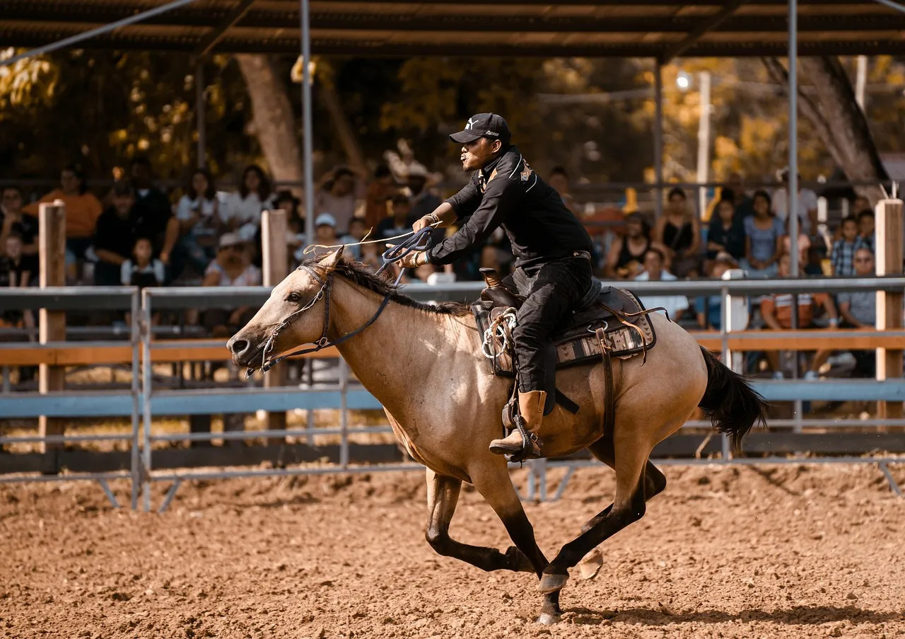 A young rider on a sorrel Quarter Horse turning hard in a dusty arena in front of a crowd